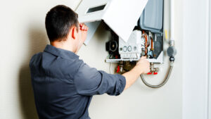 Man in grey shirt working on a wall-mounted Boiler.