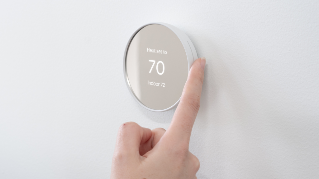 Photo of a hand using smart heating controls on a wall surface