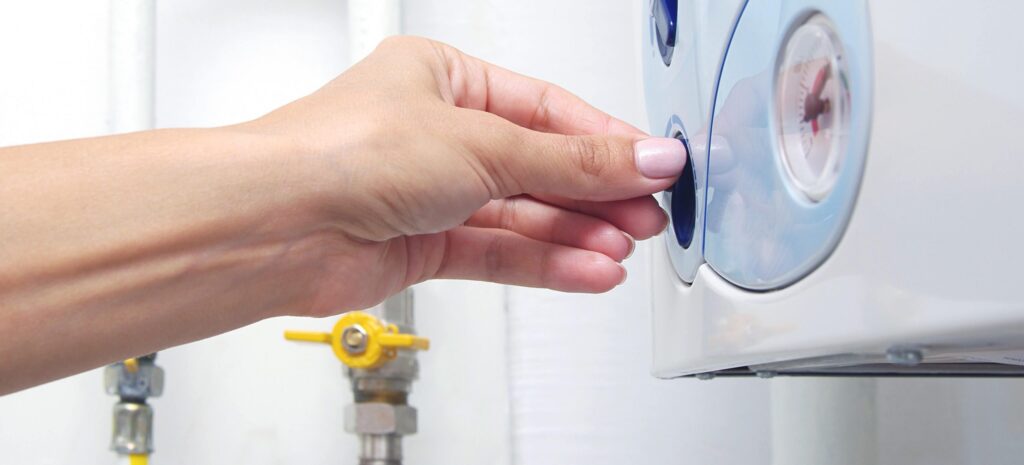 picture of a hand turning the switch on the front of a central heating combi boiler
