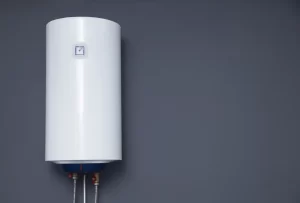 A wall-mounted electric boiler with inlet and outlet pipes on a grey background.