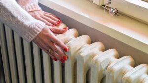 Image of cold fingers touching a cold central heating radiator